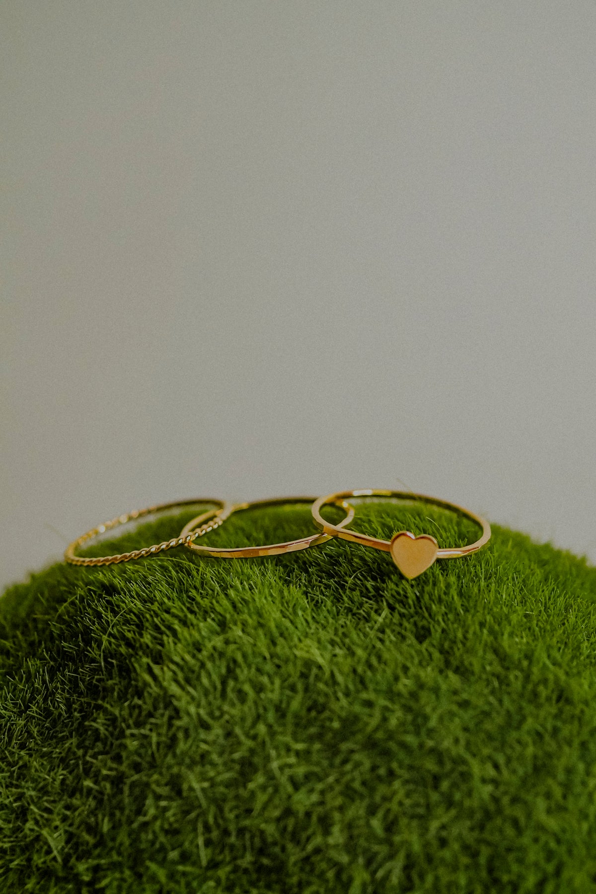 Gold heart-shaped ring on a green textured surface with a neutral background