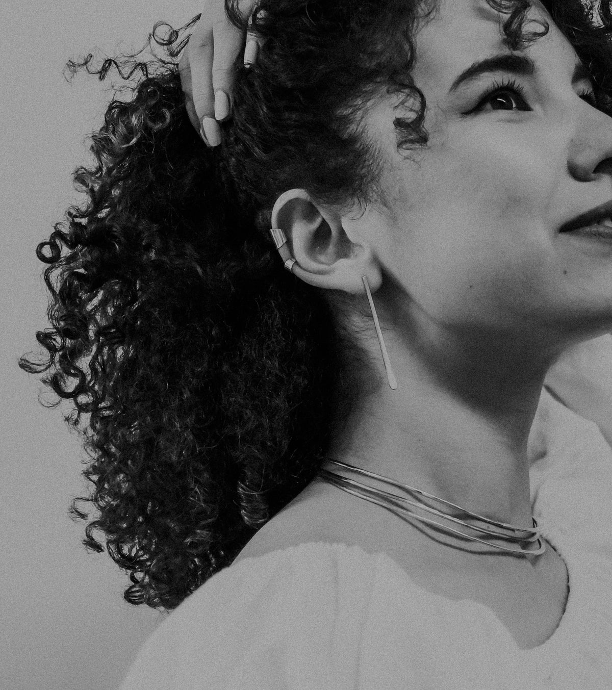 Black and white close-up of a woman with curly hair and earrings.