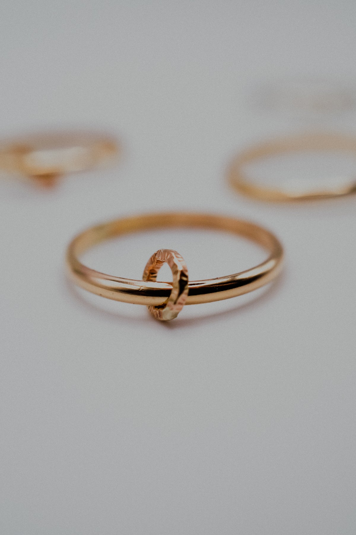 Gold ring with a link on a light gray background