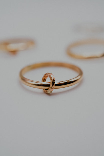 Gold ring with a link on a light gray background